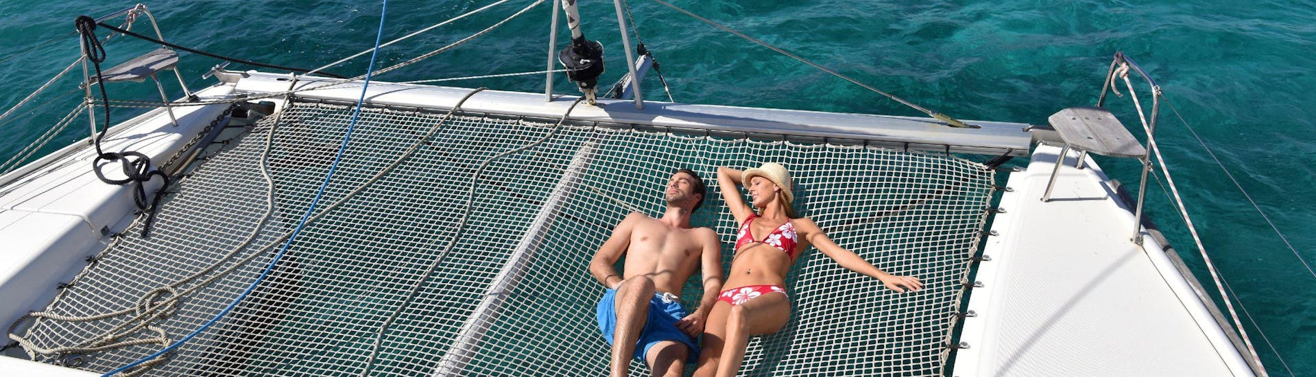 Un couple prend un bain de soleil sur un catamaran.