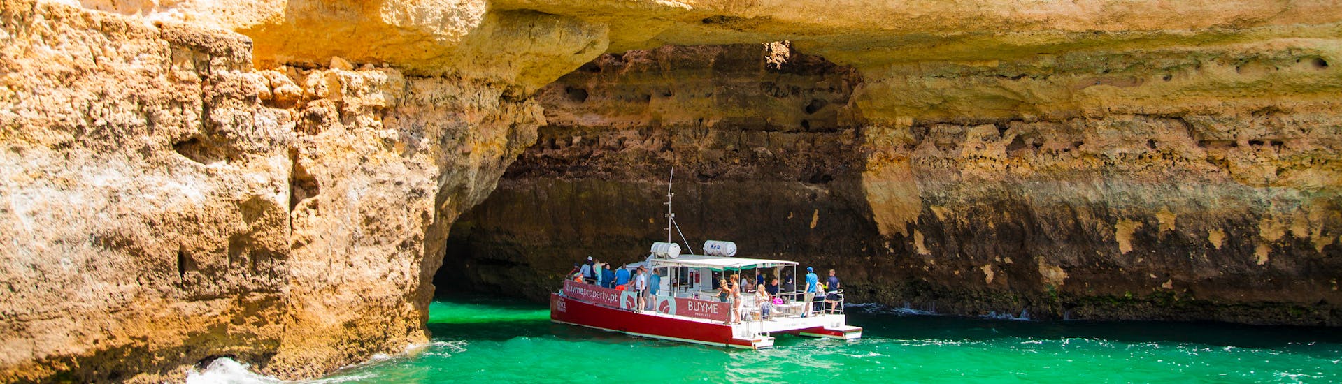 Mehrere Boote besuchen während einer Bootstour eine Höhle am Ufer.