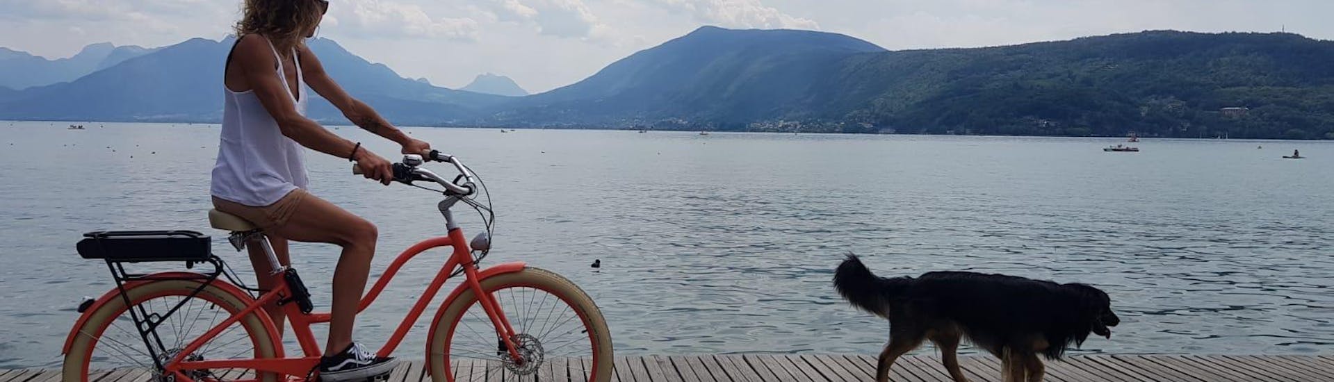 Oranje fiets rijdt langs het water met een zwarte hond voorop door Cayoti.