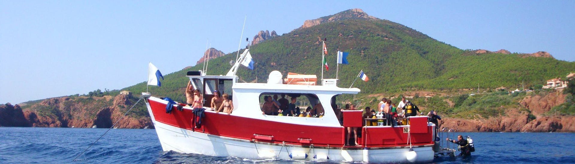 View of the Dive Center La Rague boat in front of the Estérel massif used for snorkeling trips and diving courses near Cannes.