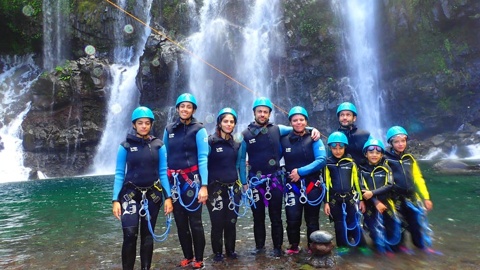 Participants on a canyoning trip on Reunion Island with Cilaos Aventure are taking a picture in front of a waterfall.
