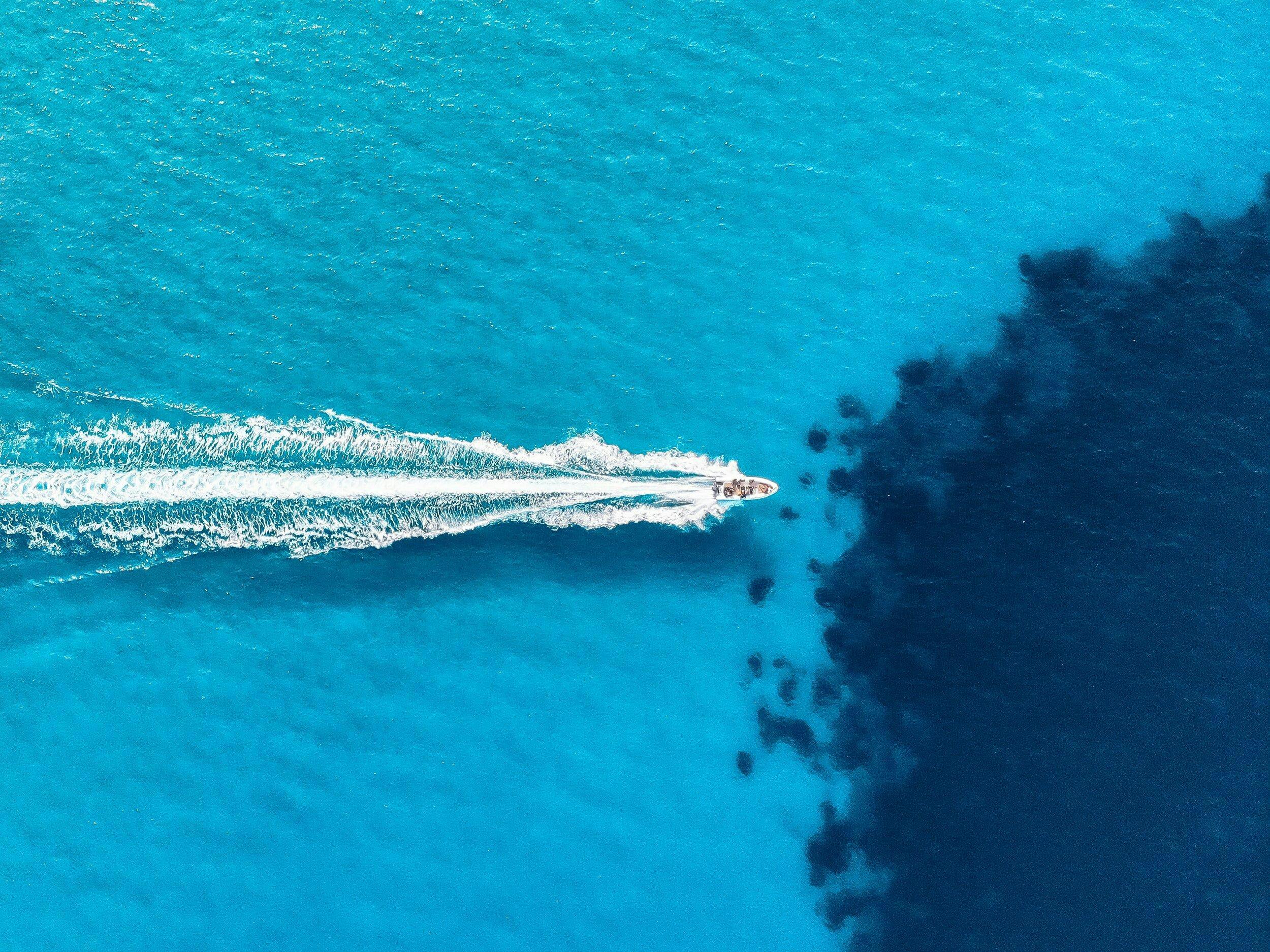 Corfu Adventures Here we have an aerial view of a boat cruising the blue mediterrean sea with Corfu Adventures.