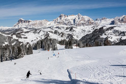 Adults and kids skiing in Corvara ski resort.