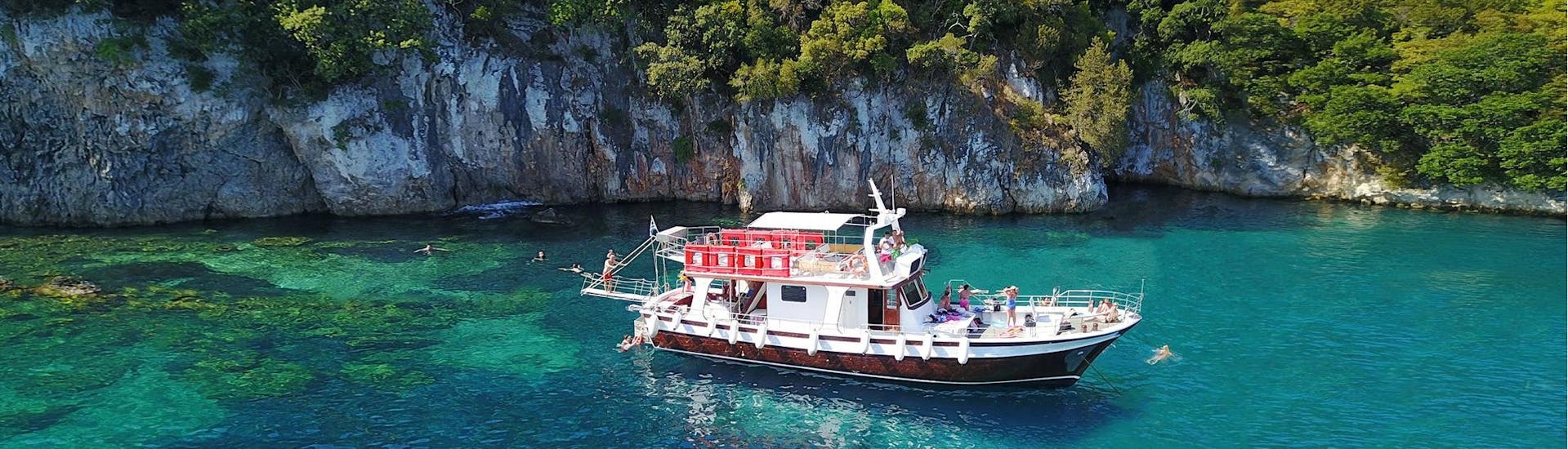 Das moderne Holz-Boot, das für die Bootstouren von Zephyros Milos verwendet wird, steht in einer Bucht mit kristallklarem Wasser in Milos.