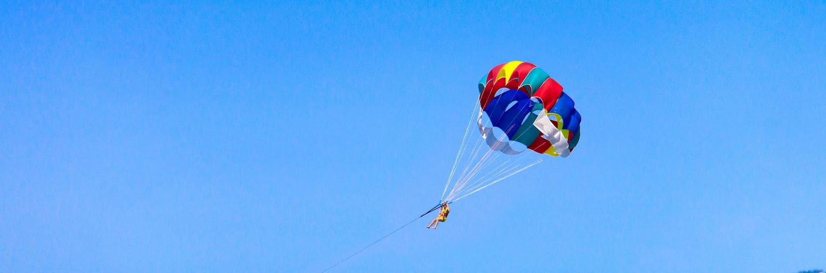 Un homme profite de la magnifique vue à 360 degrés en faisant du parachute ascensionnel avec Crazy Sports à Santorin.