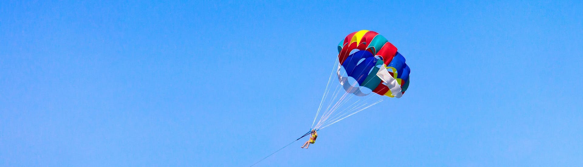 A man is enjoying the magnificent 360 degree views whilst parasailing with Crazy Sports in Santorini.