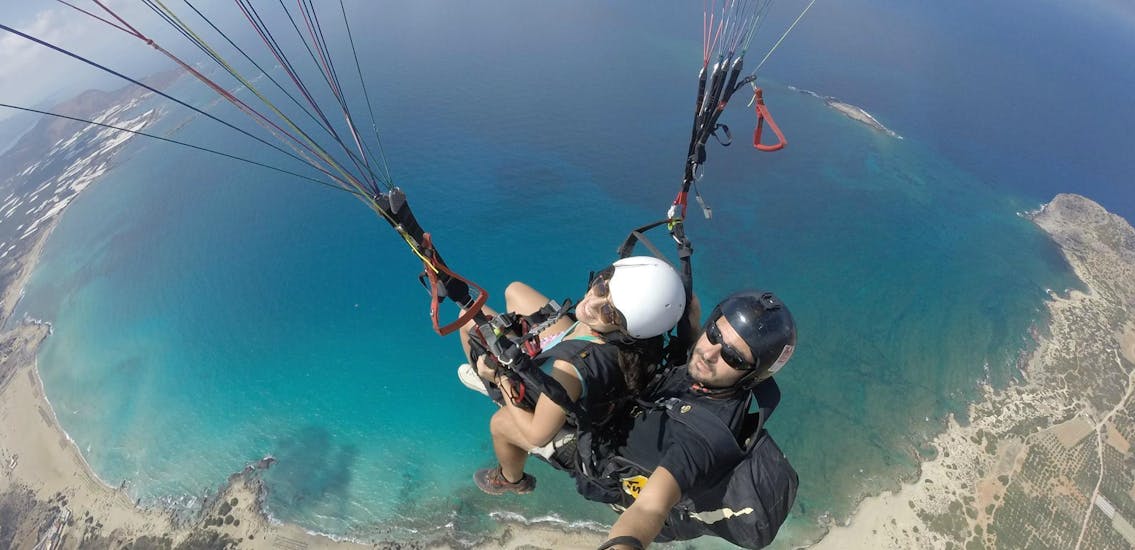 A passenger is enjoying flying high in the blue sky above the island of Crete with an certified tandem pilot from Cretan Paragliding. 