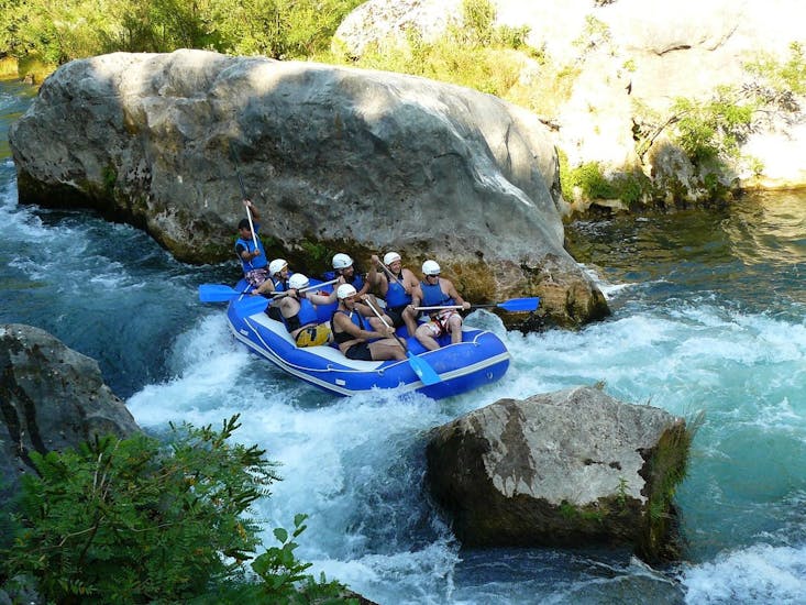 Degli amici si stanno divertendo sul fiume Cetina pagaiando insieme durante una delle attività organizzate da Croatia Rafting.