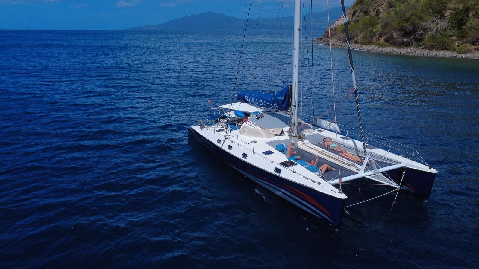 4 personas se relajan sobre las redes del catamarán de Spi Sea Sailing.