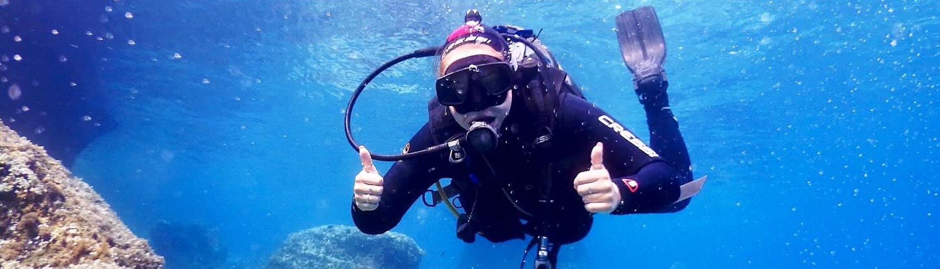 A person diving with the thumbs up underwater 
