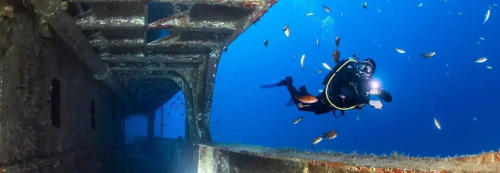 A person diving next to a wreck with Dive Vision Malta. 