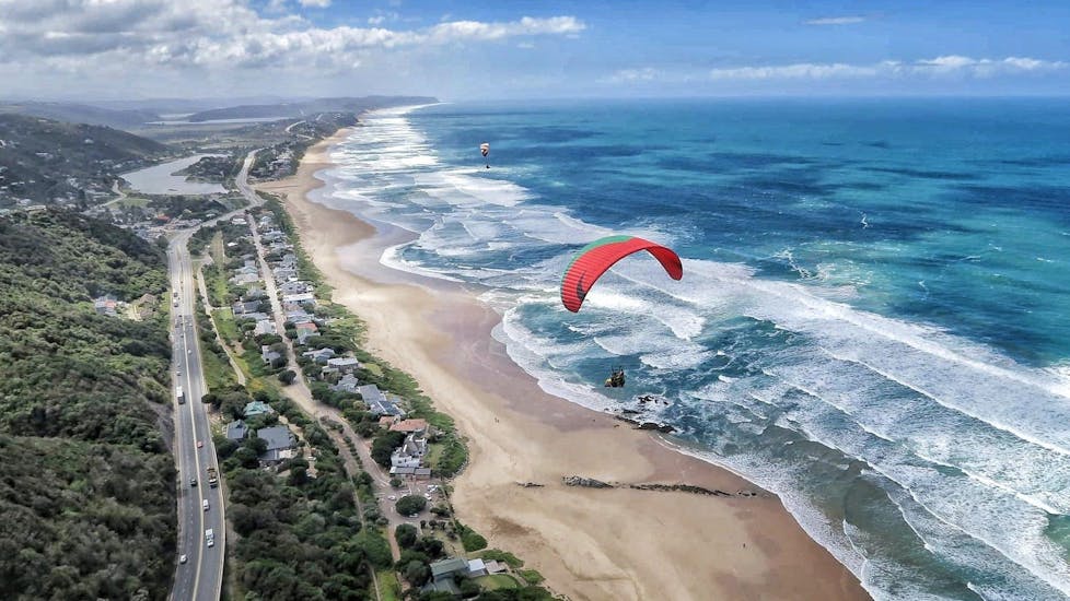 Experienced tandem pilot from Dolphin Paragliding Wilderness is flying with a client above the roaring ocean.