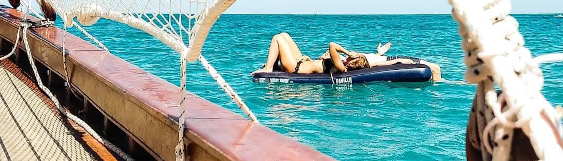 Due partecipanti stanno prendendo il sole durante il giro in barca a vela privato con Don Mar Sailing Numana.
