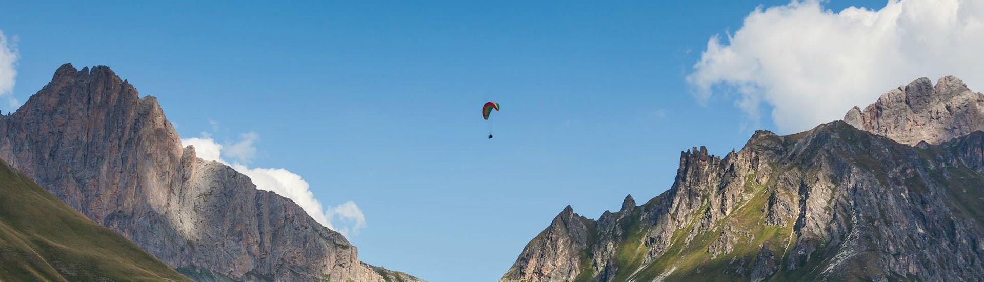 A paragliding pilot from Emotion'Air is flying high above Serre Chevalier during a tandem paragliding flight.