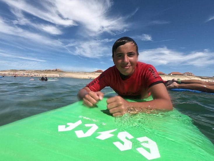 Un surfeur est sur sa planche de surf dans l'eau pendant ses cours de surf sur la plage des Sablères avec l'école de surf ESCF Vieux Boucau.