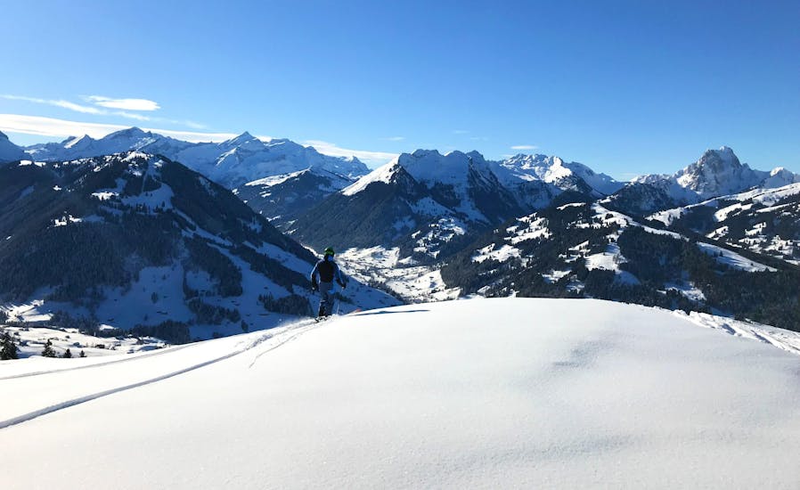 A skier is overlooking the Saanenland ski area where the ski school ESS Château d'Oex is organizing ski lessons.