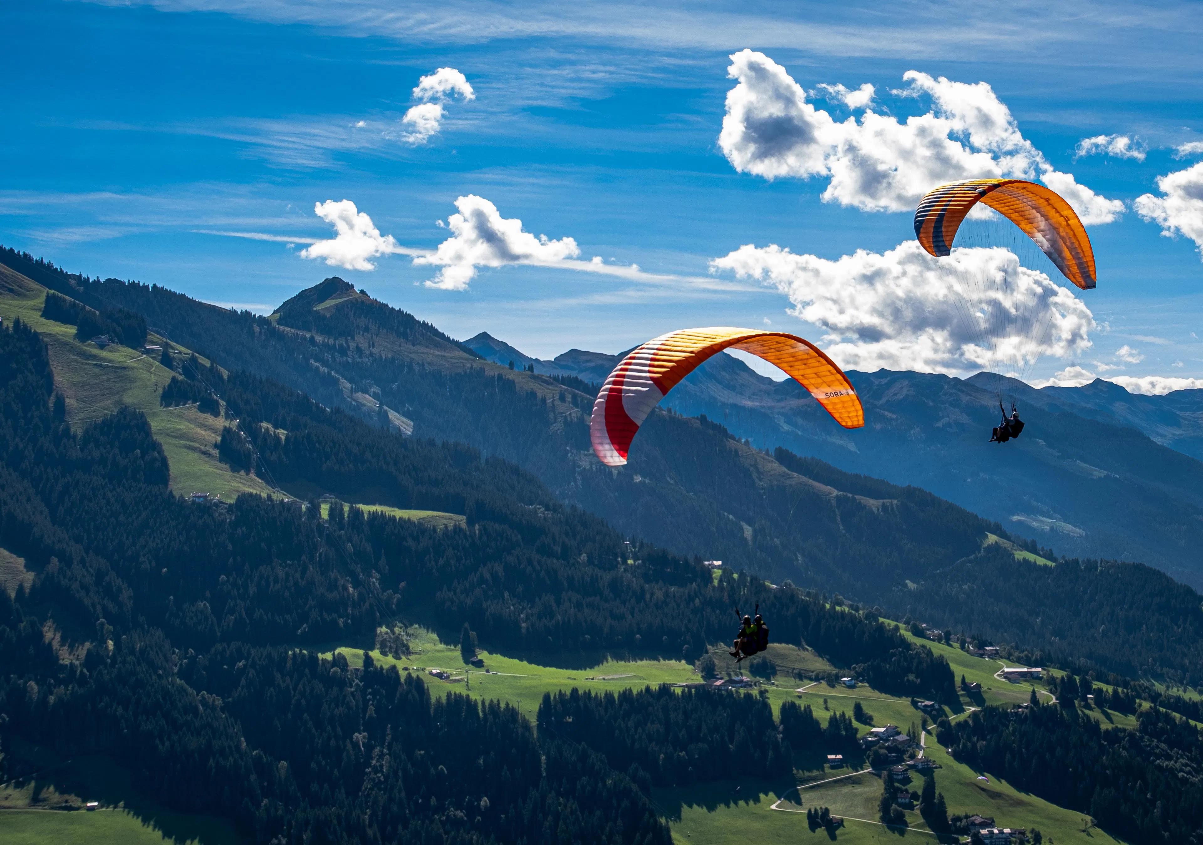 Fly Tirol Un passager et un instructeur professionnel de parapente en tandem volant au-dessus des Alpes de Kitzbühel.
