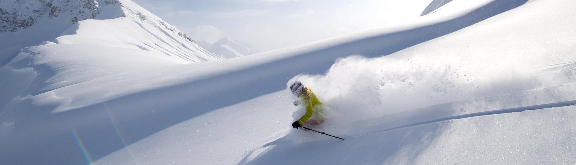 A skier is making his way down a deep powder snow slope during his off piste skiing lessons in Tyrol.