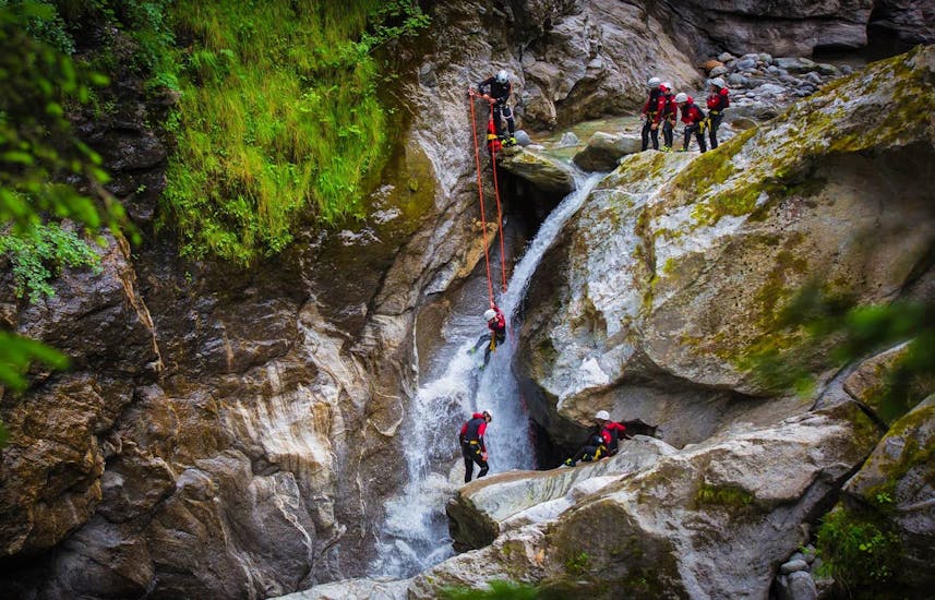 Eine Gruppe von Teilnehmern seilt sich bei einer Canyoningtour im Zillertal mit der Freiluftakademie über einen imposanten Wasserfall ab.