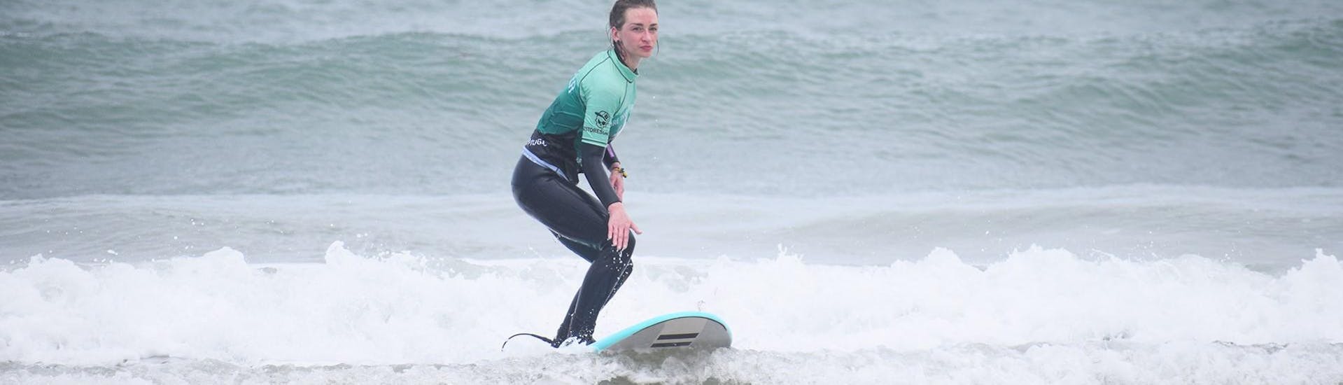 A woman coached during a private lesson by G3 Store rised on her board in a Peniche wave.