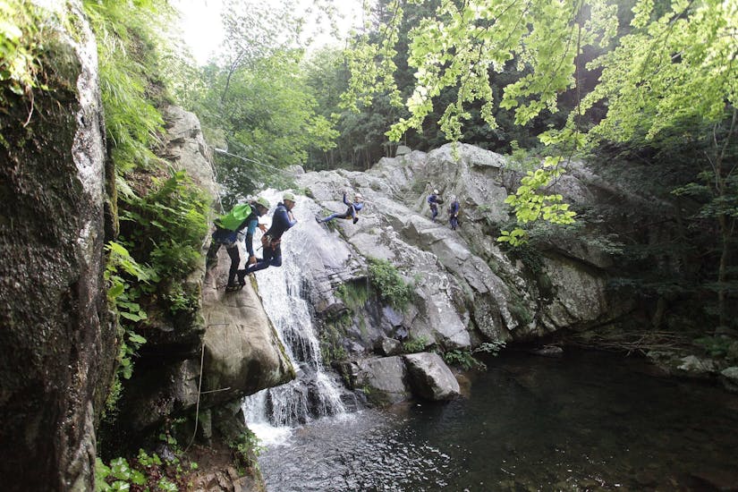 Friends are overcoming different obstacles including a zipline and jumps during one of the canyoning tour provided by Geo Ardèche Canyon.
