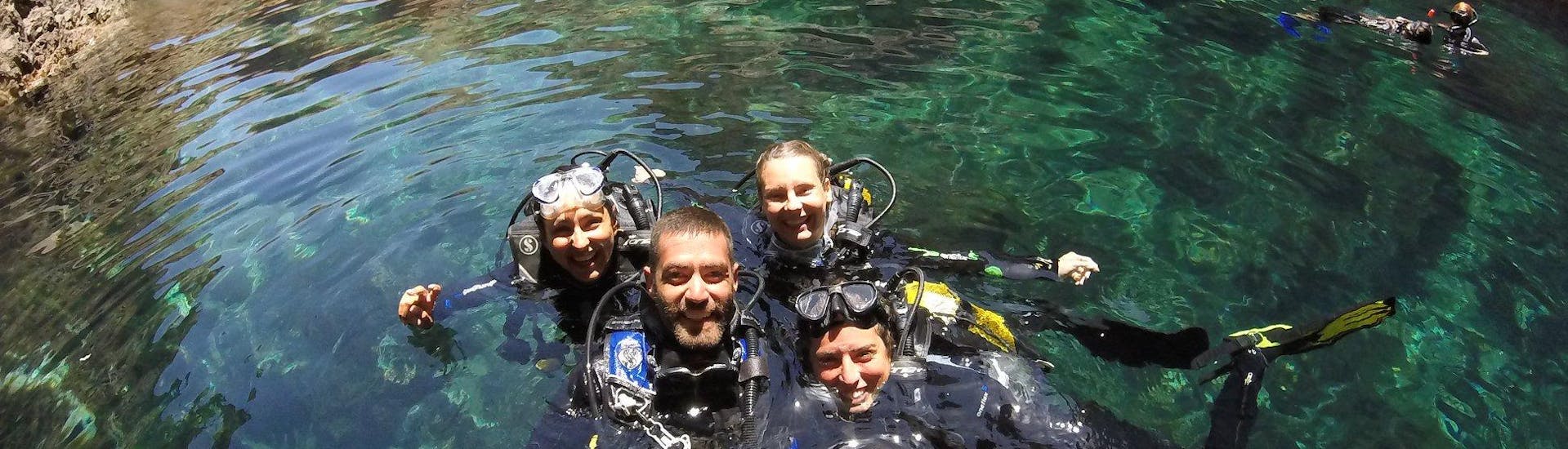 3 Teilnehmer mit ihrem Tauchlehrer im Wasser während eines Tauchgangs in Mykonos mit GoDive Mykonos.