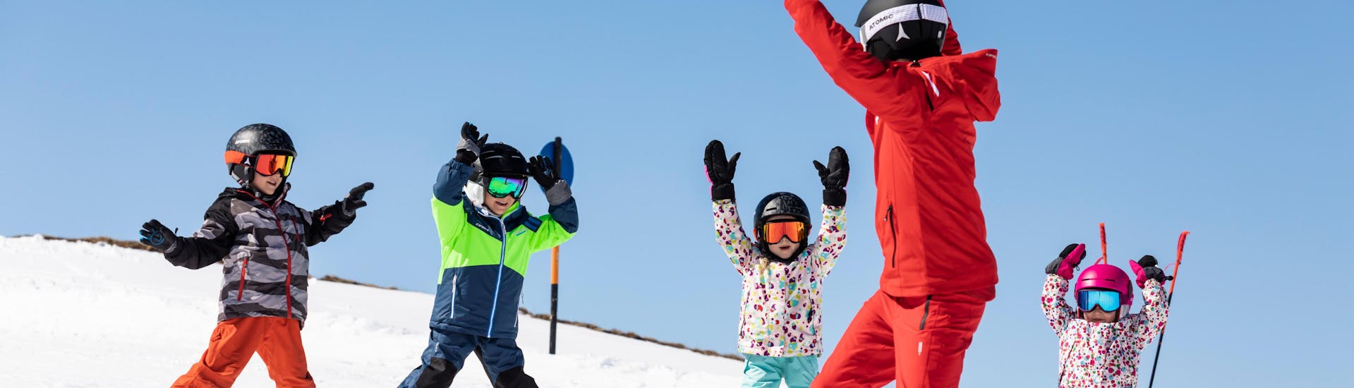 Mehrere Kinder üben das Skifahren mit ihrem Skilehrer in einem Gruppen Skikurs einer Skischule im Skigebiet Daolasa - Commezzadura.