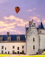 Un magnifique château à côté de la rivière du pays de la Loire avec une montgolfière au dessus.