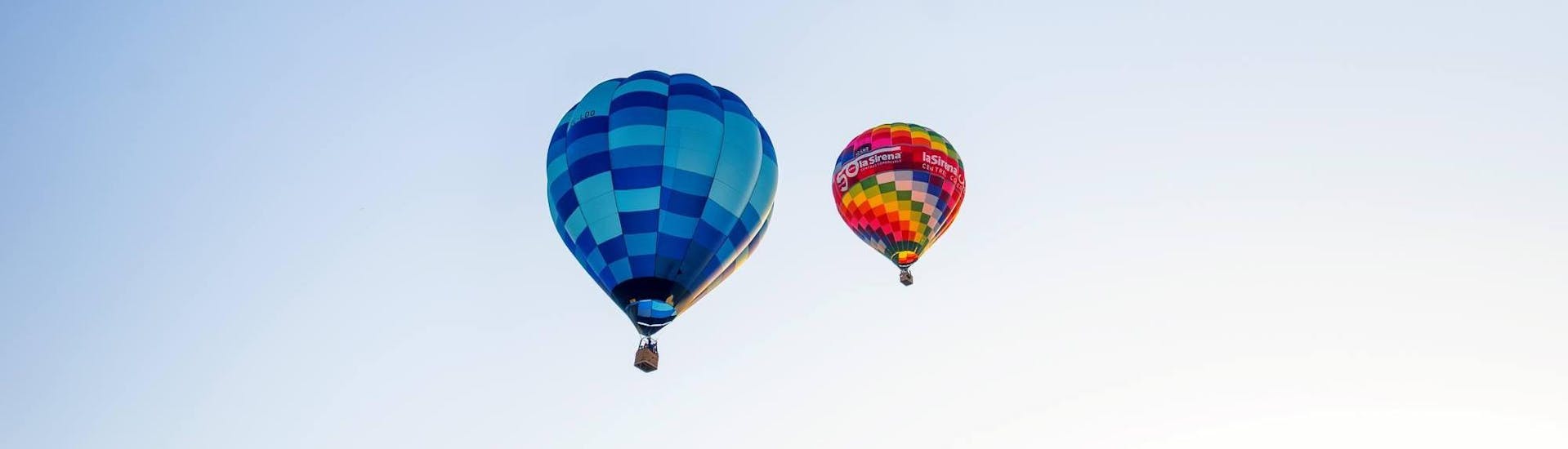 Zwei Heißluftballone von Ibiza en Globo schweben in aller Ruhe mehrere Meter im Himmel.