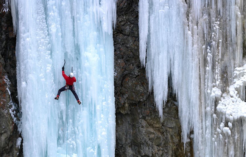 Eine Person erklimmt beim Eisklettern eine vereiste Felswand bei der Aktivität "Eisklettern Privat - Schnuppertag" mit dem Anbieter Alpinschule RocknRoll.