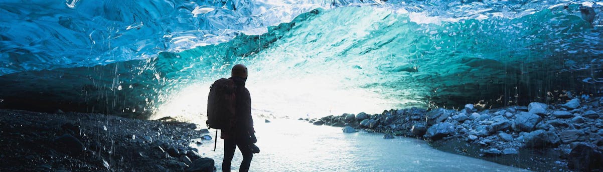 Iceland Tours & Activities SEM Hero Un homme marche dans une grotte de glace.