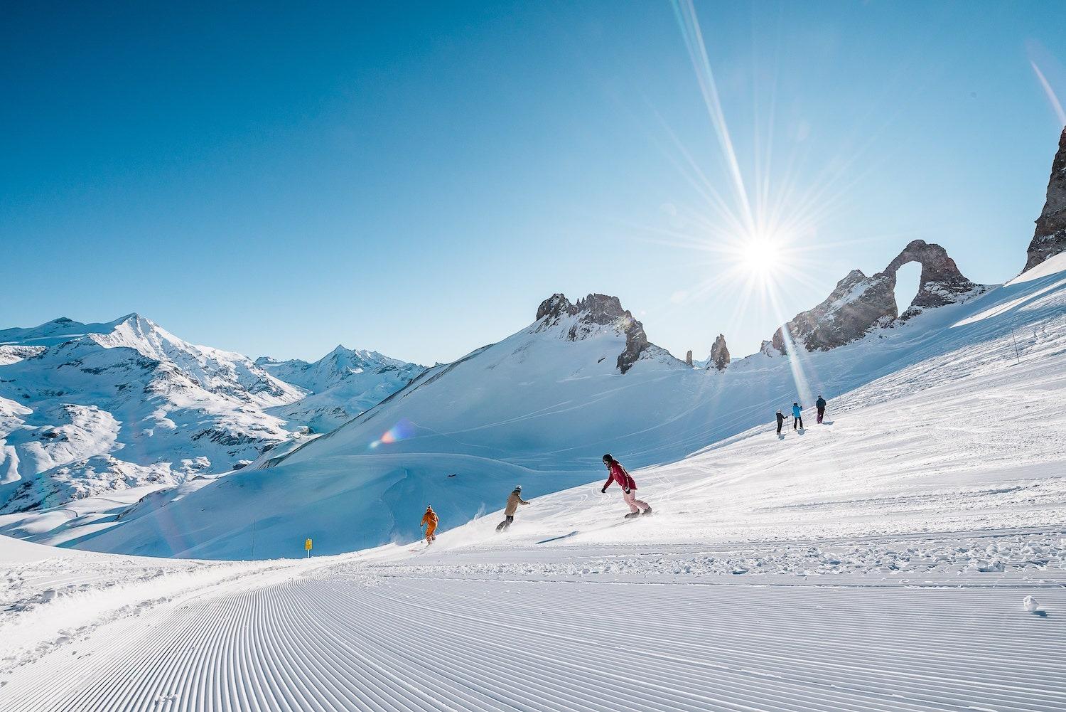 People skiing down the slopes of the Tignes resort with the Oxygène ski school under bright sunshine.