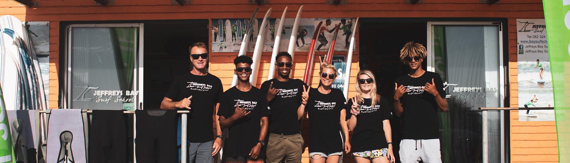 The team of Jeffreys Bay Surf School smiling posing for a picture at their base in Jeffreys Bay on the beach where they held surfing lessons, both groups and private.