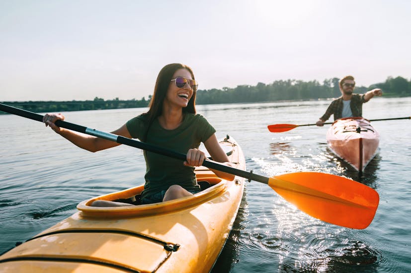 A young couple is paddling across the water as they enjoy their kayak canoe in [place].