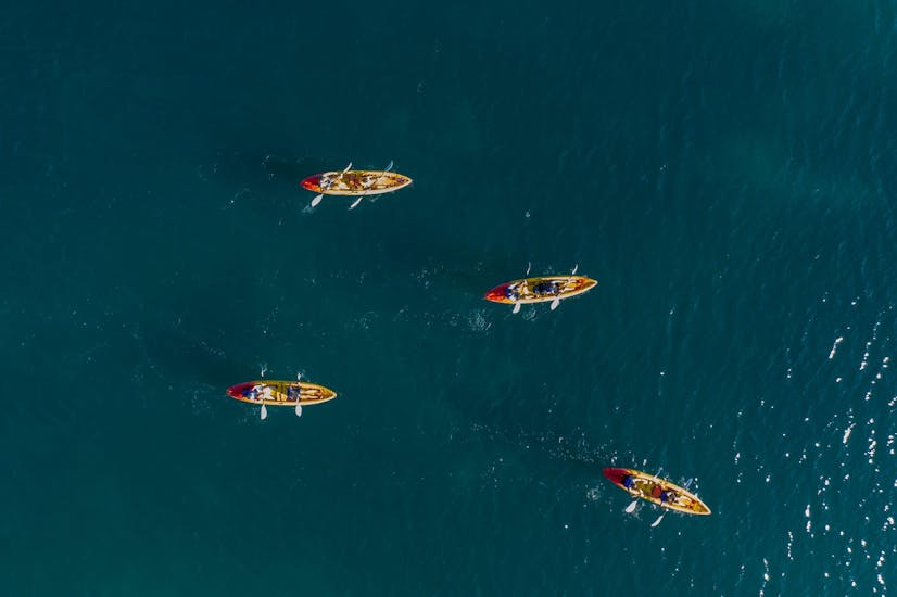 Quattro kayaks nelle acque che circondano il Parco Naturale di Capo Kamenjak a Premantura durante un'escursione con Kayaking Premantura.