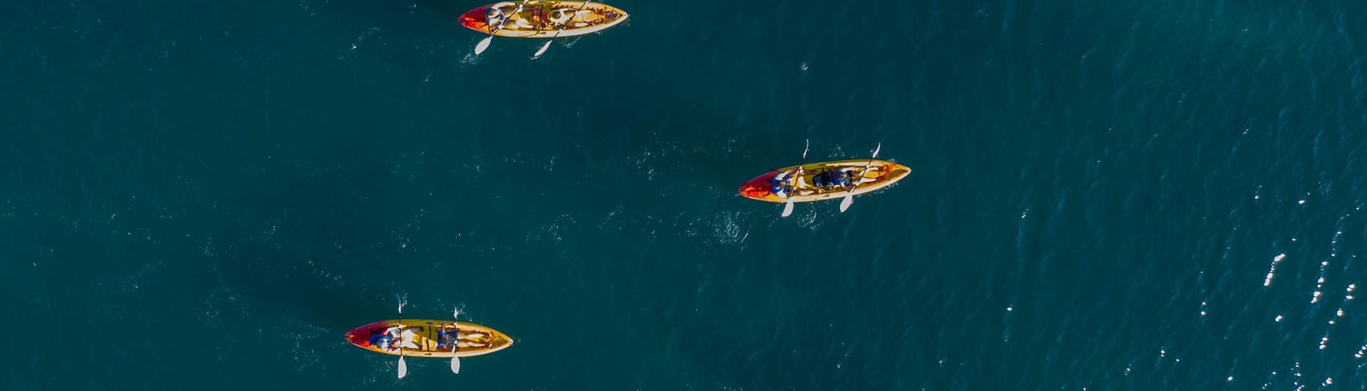 Quattro kayaks nelle acque che circondano il Parco Naturale di Capo Kamenjak a Premantura durante un'escursione con Kayaking Premantura.