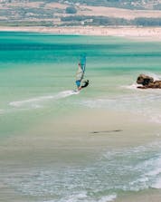 A man who is windsurfing in Tarifa can be seen riding the waves of the Strait of Gibraltar.