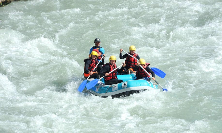 A group of friends is paddling on rapids during their rafting tour with Latitude Rafting.