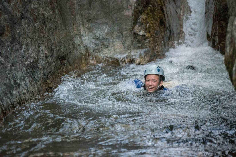 A canyoning enthusiast is swimming in a natural pool during a canyoning tour with Les Intraterrestres.