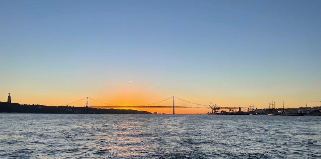 Der Blick auf die schöne Brücke 25 de abril in Lissabon bei Sonnenuntergang während einer Bootstour auf dem Fluss Tagus mit Lisbon Boats.