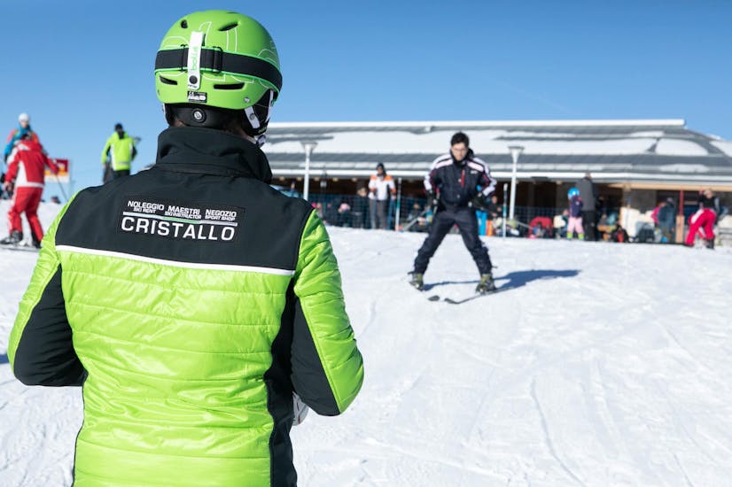A instructor of Maestri di Sci e Snowboard Cristallo - Monte Bondone is looking at a participant in the ski lessons in the ski resort of Monte Bondone.