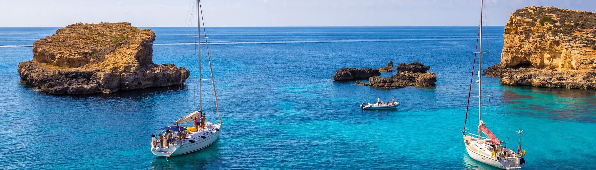 Mehrere Boote in der blauen Lagune von Malta während einer Bootsfahrt.