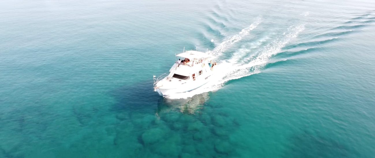 A boat is driving on the crystal clear water from Malia Cruises