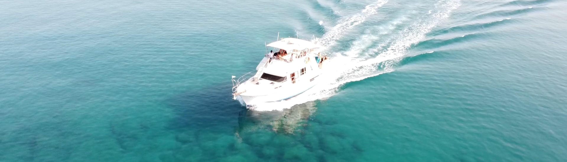 A boat is driving on the crystal clear water from Malia Cruises