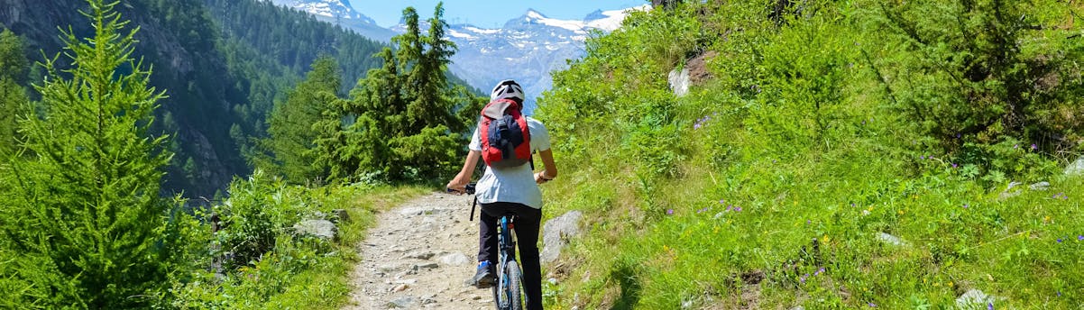 mountain-bike-valais_SEM-Resort-Hero Eine Frau ist mit dem Fahrrad vom Fahrradverleih im Wallis in der Schweiz unterwegs.