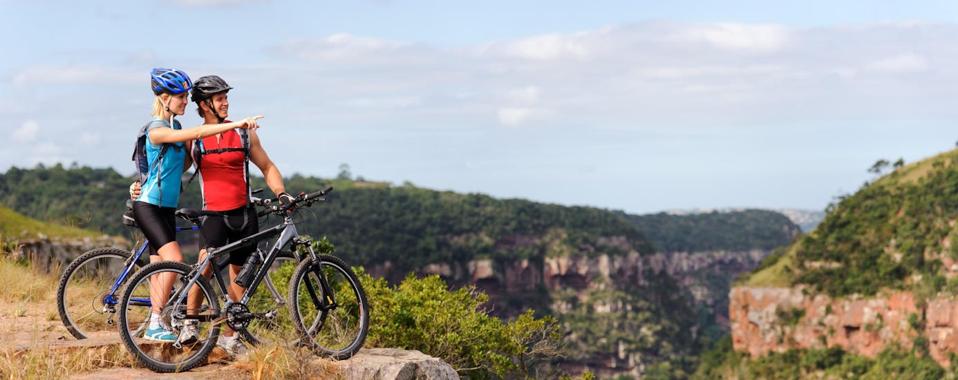 Couple is mountainbiking and enjoying the view during a stop