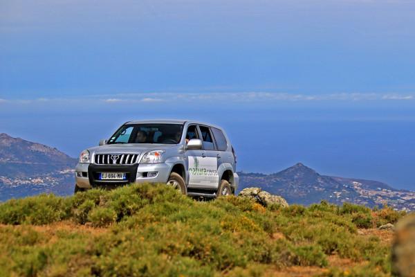 Ein Natura Corsa 4x4 auf dem Gipfel eines Berges mit einem Panoramablick auf die Agriates-Wüste und das Meer.