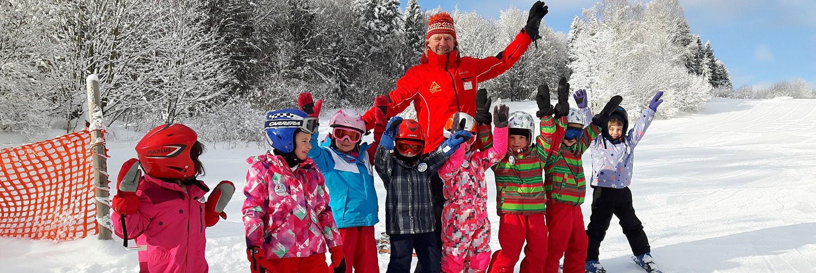 Ski instructor and kids holding up hands at G&S Snowsportschool Mitterdorf.