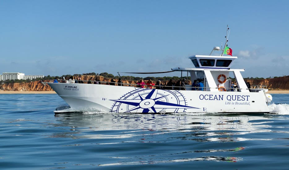 An Bord eines modernen Bootes von Ocean Quest genießt eine Gruppe von Touristen die wunderschöne Aussicht auf die felsige Küste der Algarve.