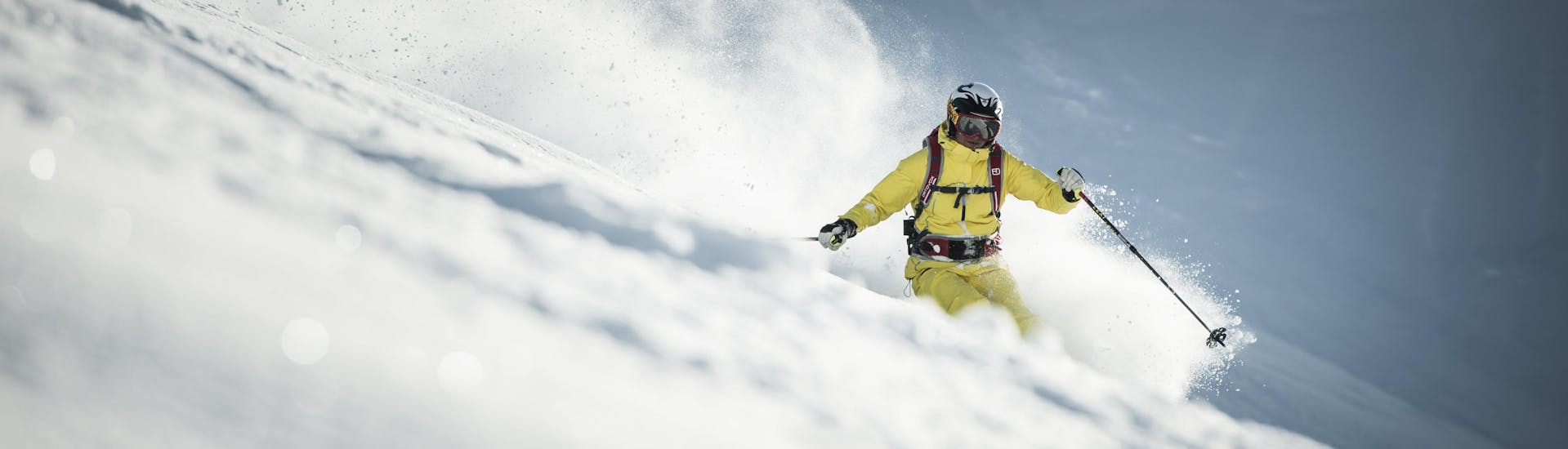 Een skiër maakt tijdens zijn off-piste skilessen een afdaling in diepe poedersneeuw.